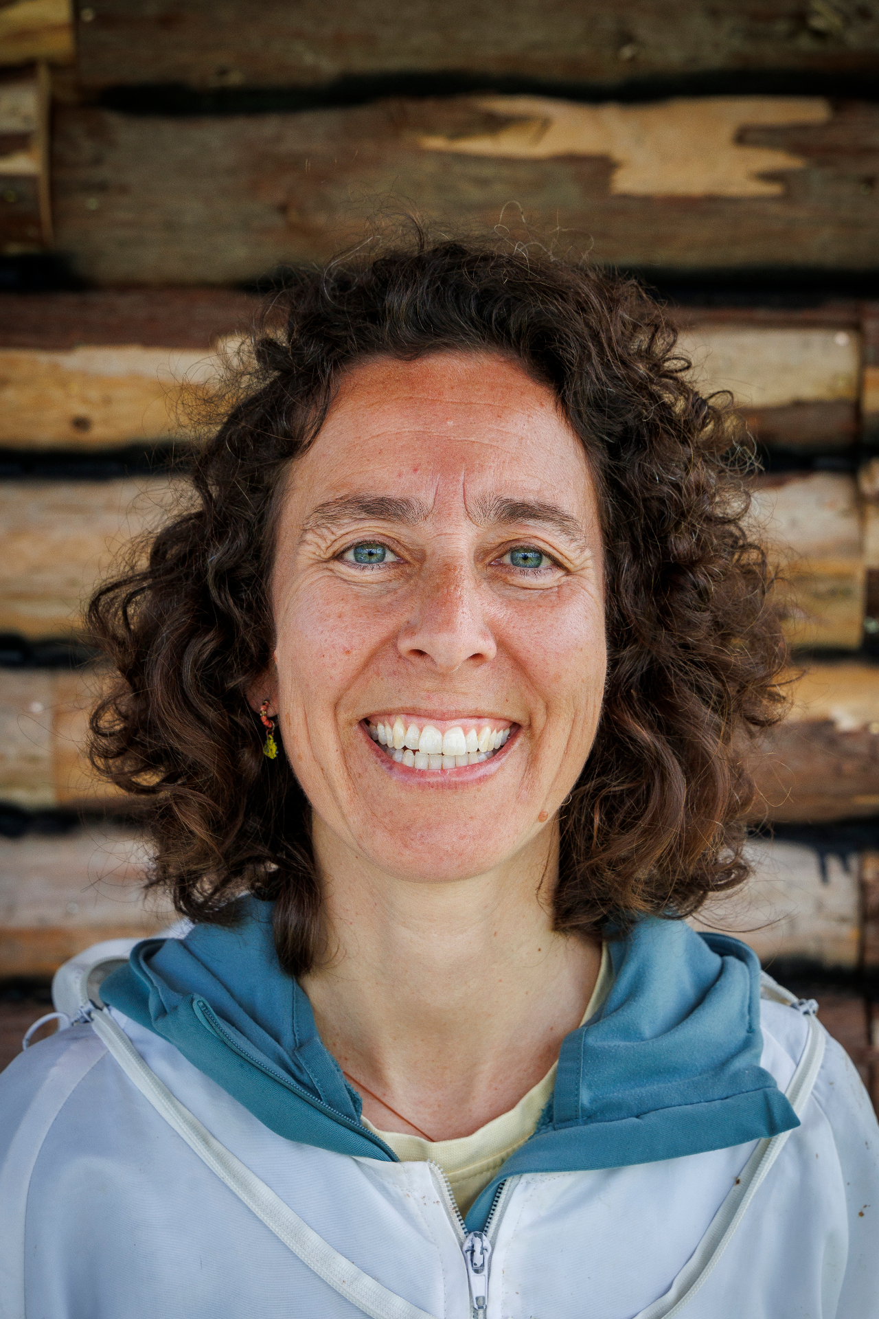 Carolina Ferraz, close-up portrait against a firewood background